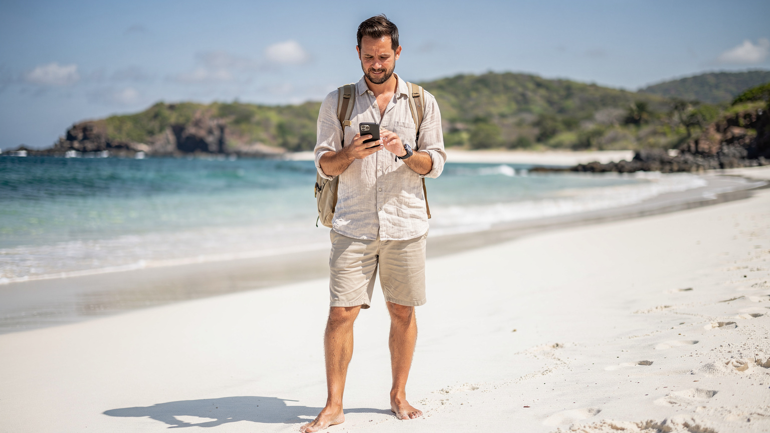 Un viajero con su teléfono en mano, consultando un mapa en la playa de Los Frailes, cerca de Machalilla, con la tranquilidad de una conexión estable.