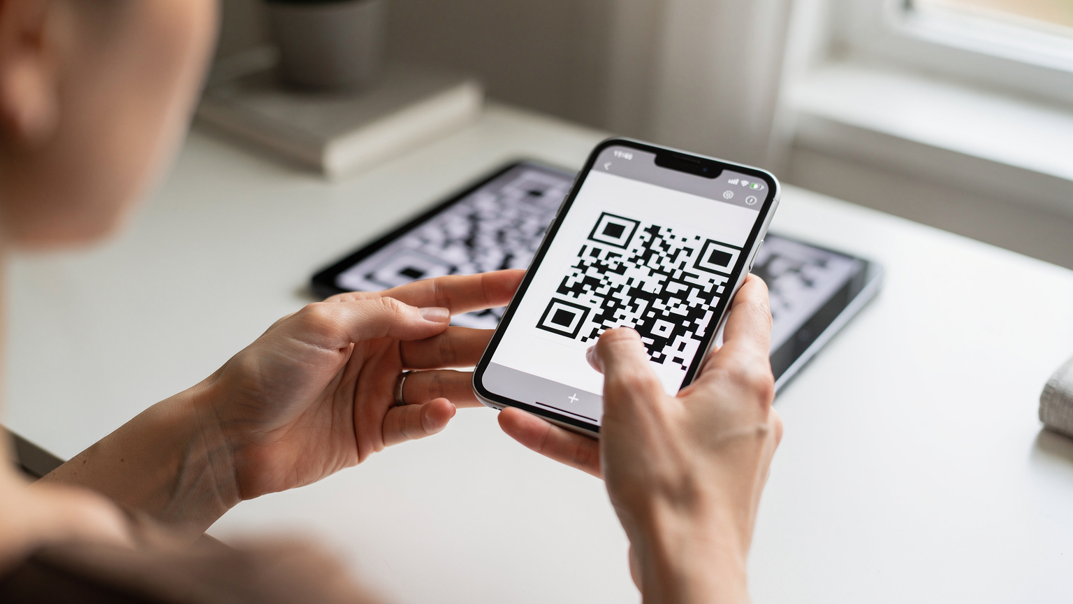 iPhoneの画面にeSIMのQRコードをスキャンしている様子。指が画面に触れている。