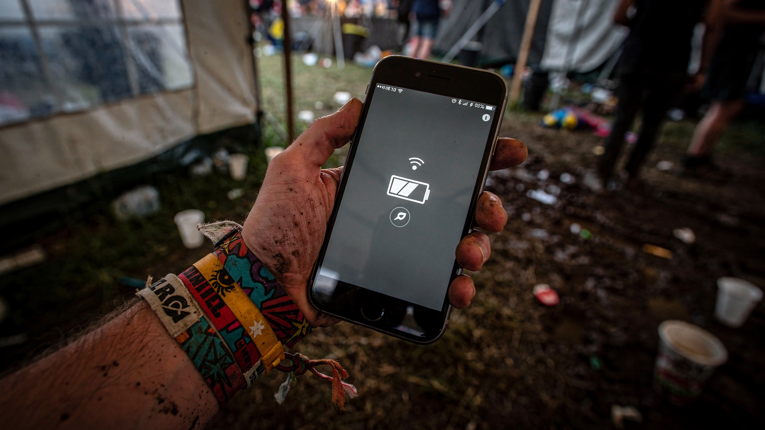 Et festivalarmbånd pryder et håndled, der holder en smartphone med lavt batteri-ikon, der illustrerer udfordringen med at holde strøm på en festival.