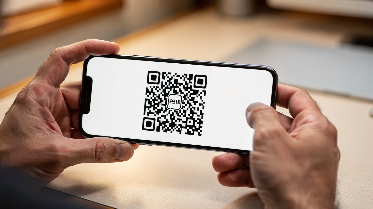 Eine Nahaufnahme zeigt Hände, die ein Smartphone halten, auf dem eine Cellesim-eSIM-Installation angezeigt wird, mit einem QR-Code im Fokus.