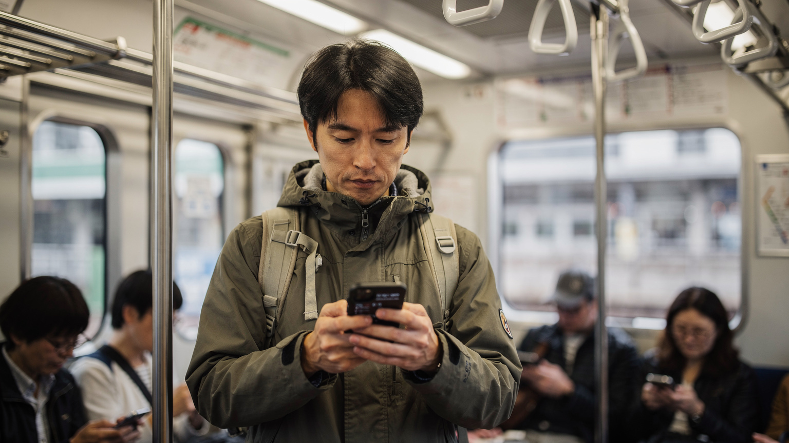 A traveler using a local transit app on their phone, surrounded by diverse passengers on a Tokyo Yamanote Line train, highlighting cultural immersion and reliance on connectivity.