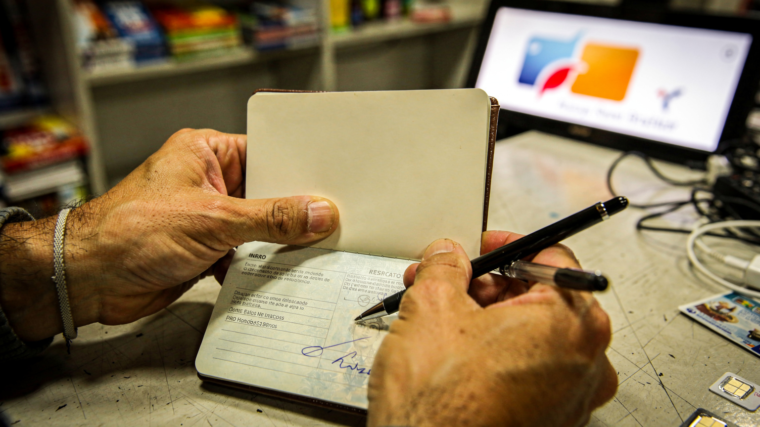 As mãos de um expatriado segurando um passaporte e um formulário para preencher, com o logotipo de uma operadora de celular equatoriana desfocado ao fundo, simbolizando a burocracia da aquisição de um chip físico.