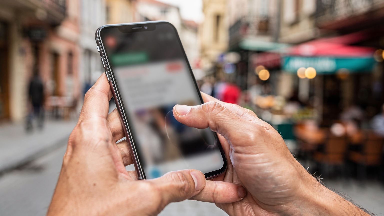 Руки держат смартфон с открытым приложением Cellesim для управления eSIM, на фоне размытого фокуса улицы Стамбула.