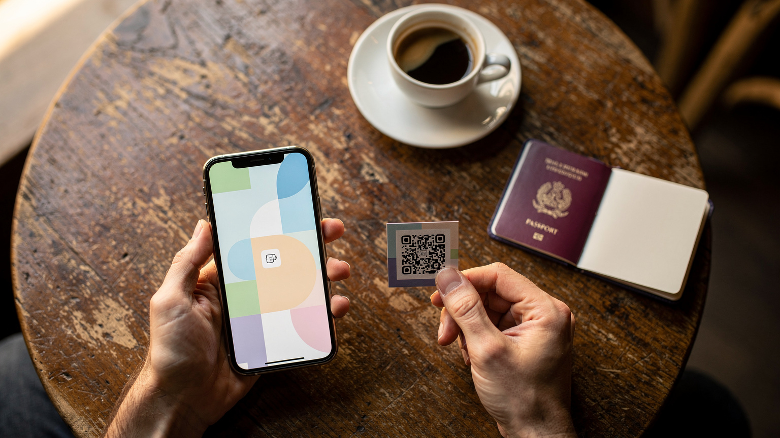 Un primo piano ravvicinato di mani che installano una eSIM scansionando un QR code su uno smartphone, con una tazza di caffè e un passaporto in sottofondo.