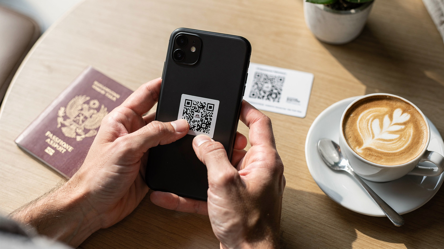 Une personne scannant un code QR pour activer son eSIM sur un smartphone, avec une tasse de café et un passeport sur une table en bois clair, évoquant la préparation d'un voyage.