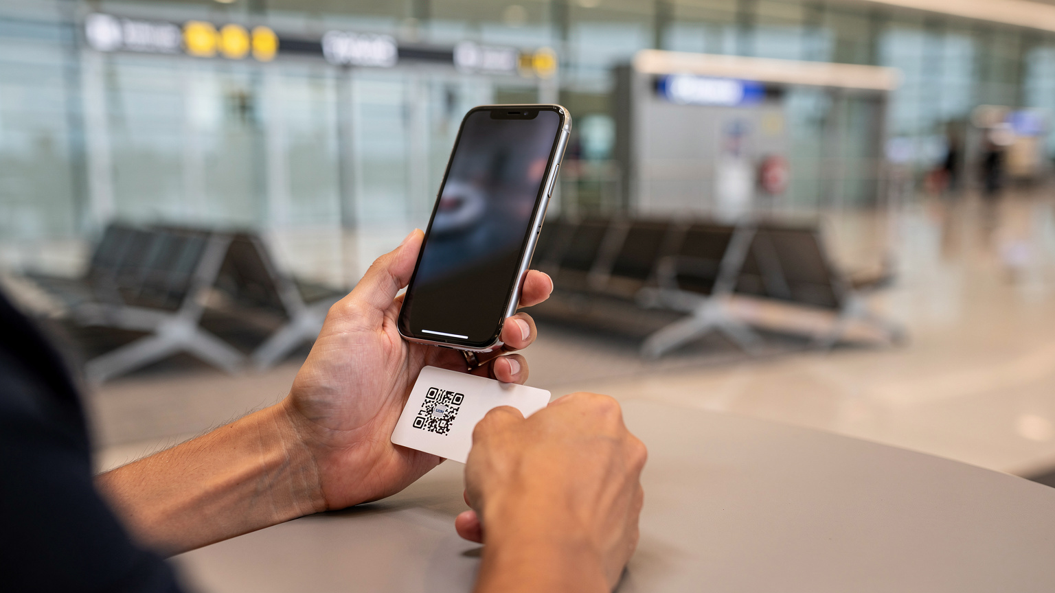 Tangan seorang traveler sedang memegang smartphone dan melakukan scan QR code untuk aktivasi eSIM di Bandara Internasional Kuala Lumpur (KLIA).