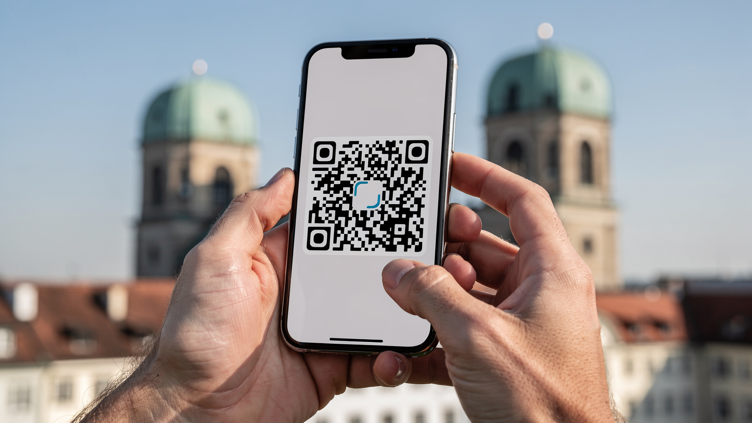 En persons hender holder en smarttelefon som viser et eSIM-installasjonsvindu, med Münchens Frauenkirche i bakgrunnen.