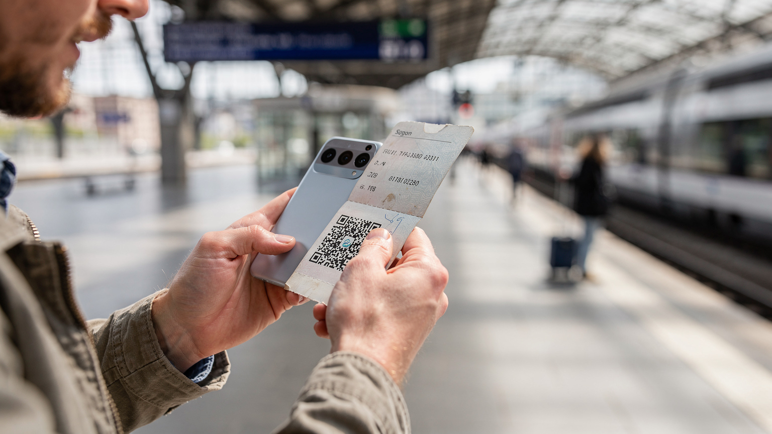 A traveler using their Pixel 9 to scan an eSIM QR code, with a backdrop of a bustling European train station platform.
