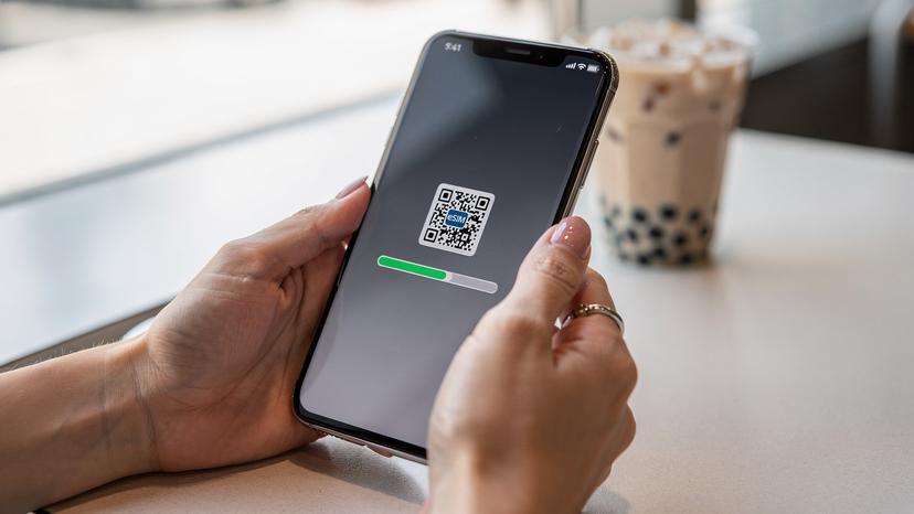 한국인 여행객의 손이 갤럭시 스마트폰으로 eSIM QR 코드를 스캔하는 모습. 화면에는 활성화 진행률 표시줄이 나타나고 있다.